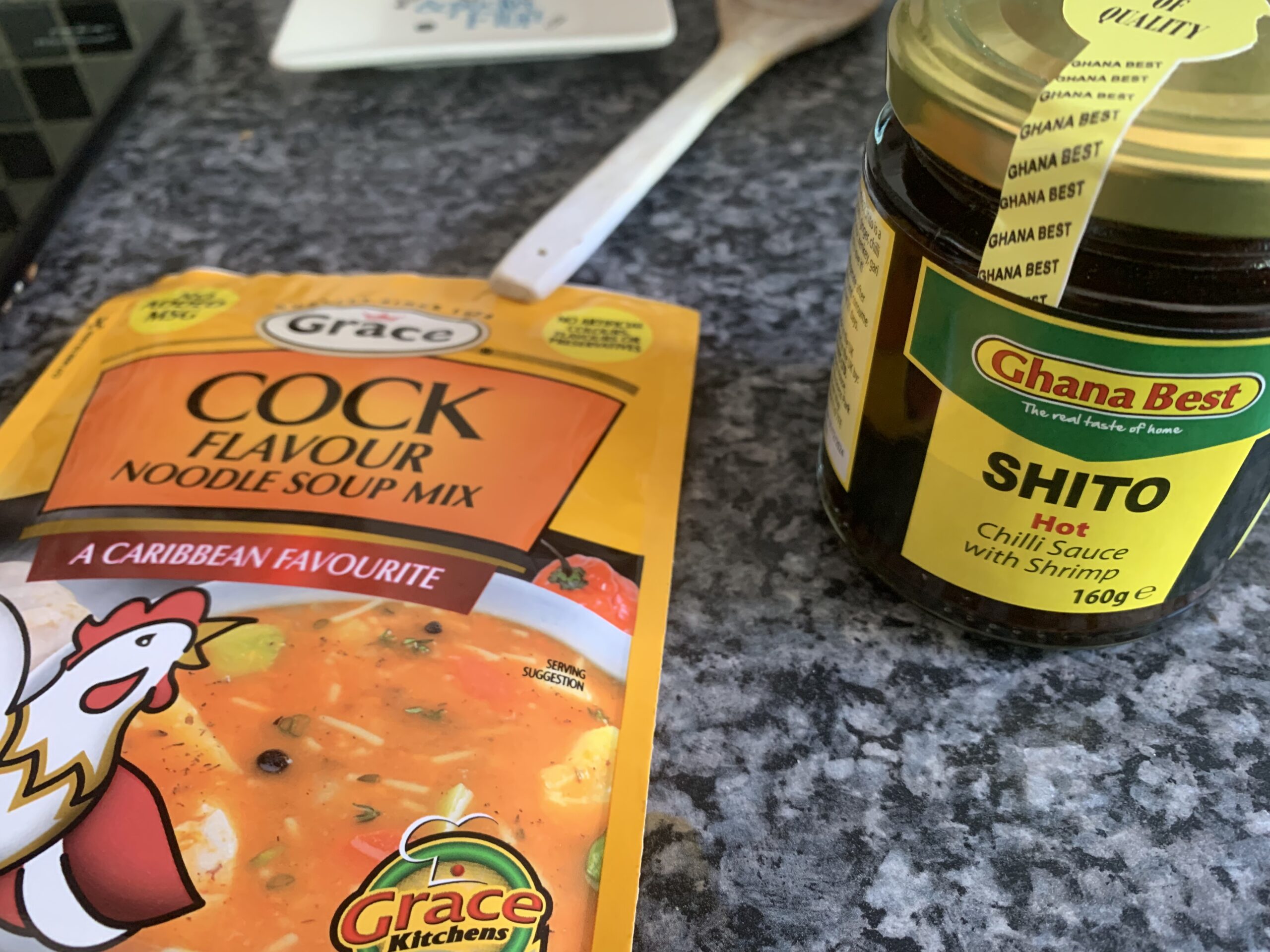 A sachet of Cock flavour noodle soup ("a Caribbean favourite") and a jar of Shito hot chilli sauce with shrimp (a Ghanaian staple).