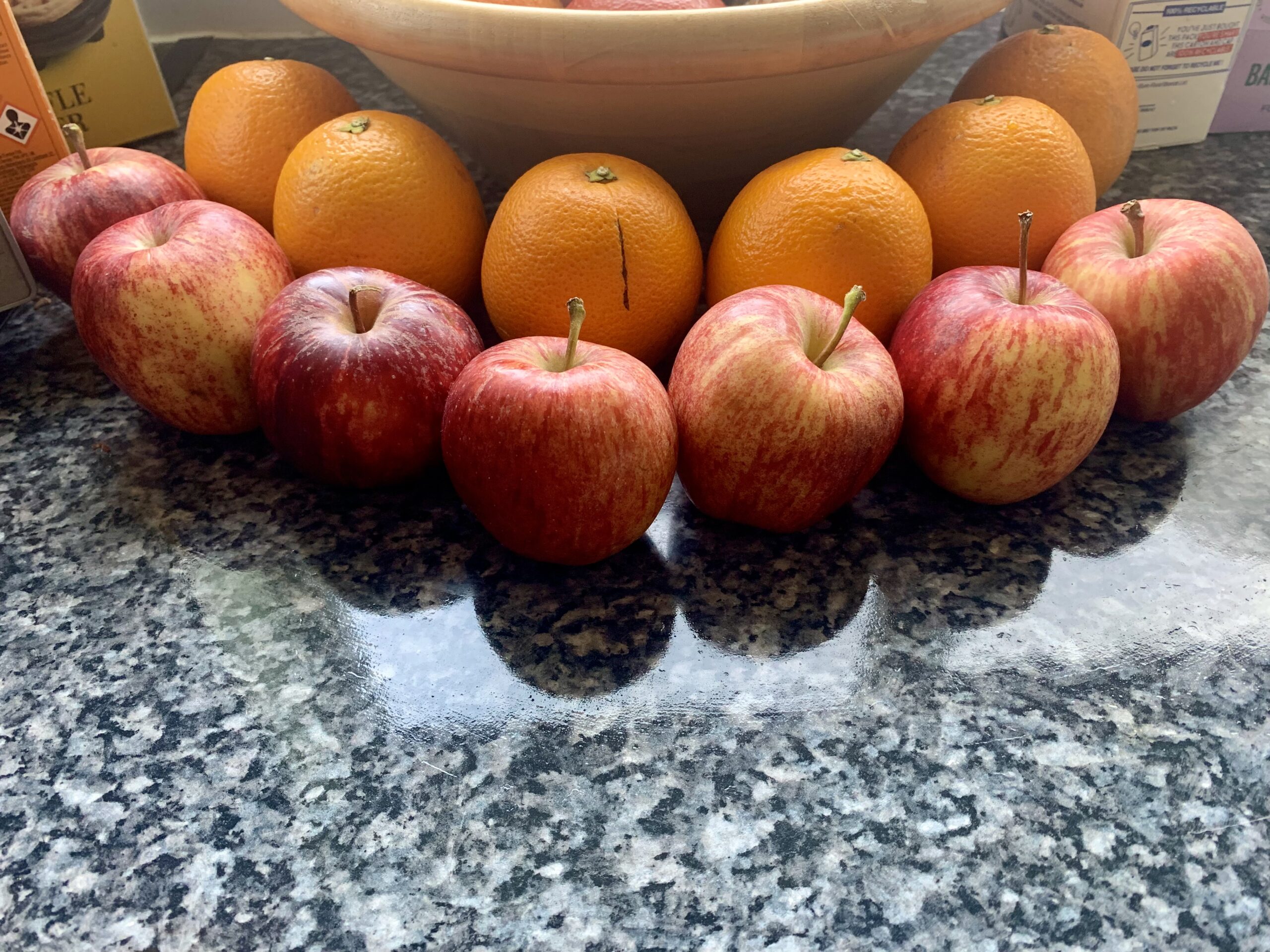 7 apples and 6 oranges in front of a fruit bowl, the contents of which aren't shown.